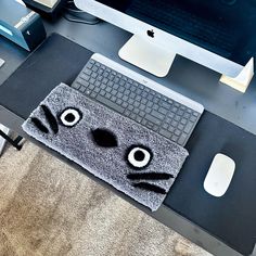 a computer desk with a cat rug on top of it and an apple monitor in the background