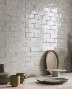 a table with plates and cups on it next to a brick wall in a room