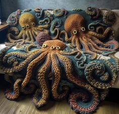 an octopus crocheted blanket is on the floor next to a couch with two eyes