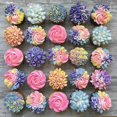 cupcakes with pink, blue and yellow frosting are arranged on a table