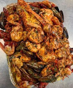 cooked shrimp and mussels in a pan on a silver surface with tongs