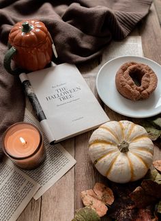 a table topped with books and pumpkins next to a plate filled with doughnuts