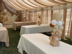 there are many balloons and teddy bears on the tables in this room with white tablecloths