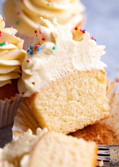 cupcakes with white frosting and sprinkles are on a plate