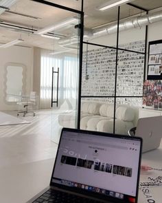 an open laptop computer sitting on top of a white table in front of a glass wall