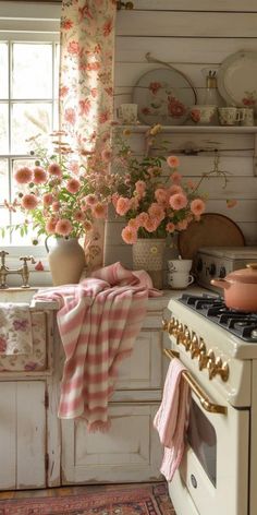 a kitchen with pink flowers on the window sill and an old stove top oven