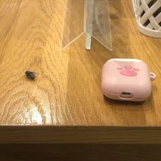 a small insect sitting on top of a wooden table next to a pink phone case