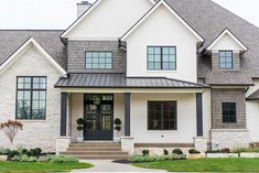 a white house with gray trim and black shutters on the front door is shown