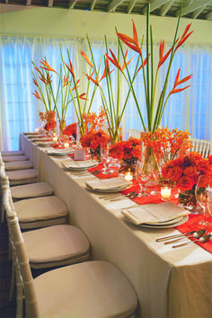 the table is set with red flowers and candles