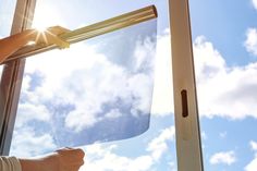 a person is holding up a window with the sun shining through it and pointing at something in front of them