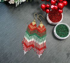 red, white and green seed beaded earrings next to christmas ornaments on grey surface