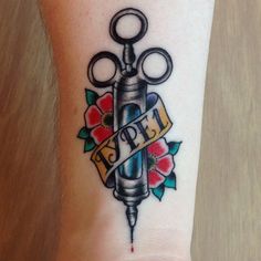 a small tattoo on the wrist of a person with scissors and ribbon around their ankles