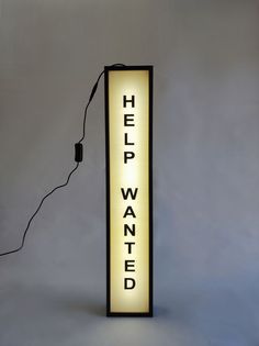 a lamp that has the words help wanted lit up on it with a cord attached to it