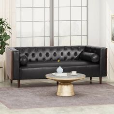 a living room with a black leather couch and coffee table in front of the window