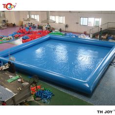 an inflatable swimming pool surrounded by other toys and equipment on the floor at a factory