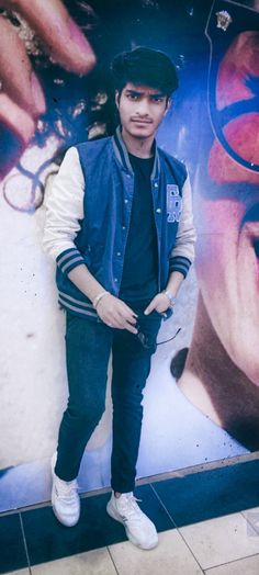 a young man standing in front of a poster