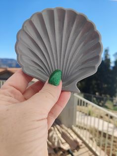 a person holding up a green shell shaped object