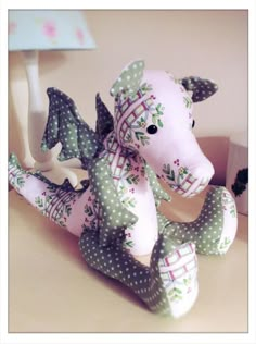 a pink stuffed animal sitting on top of a table next to a white wall light