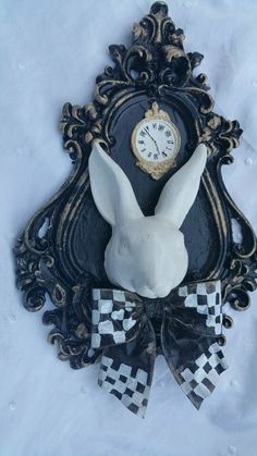 a clock with a white rabbit head on it's face in front of a black and gold frame