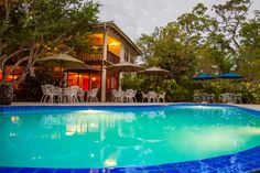 an empty swimming pool in front of a house with tables and chairs next to it