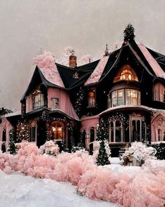 a large pink house covered in snow and christmas lights