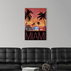 a living room with black couches and a painting on the wall that says miami