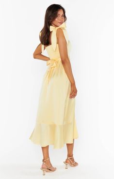 a woman is wearing a yellow dress with a bow at the neckline and back