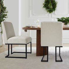 a dining room table with two chairs and a wreath on the wall in the background