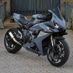 a black motorcycle parked on top of a brick road