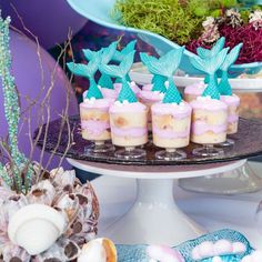 there are many desserts on the table with blue and pink frosted cupcakes