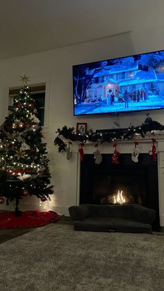 a living room with a christmas tree and a flat screen tv above the fire place