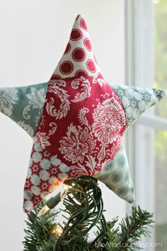 a red and white star ornament hanging from a christmas tree