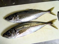 two fish sitting on top of a cutting board