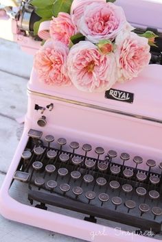 an old fashioned pink typewriter with flowers on top