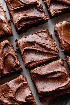 chocolate brownies are cut into squares on a sheet of baking paper, ready to be eaten