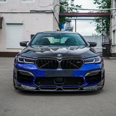 a blue bmw car parked in front of a white brick building with an open garage door