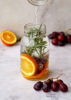 a glass jar filled with fruit and herbs