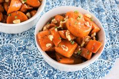 two bowls filled with carrots and nuts on top of a blue and white cloth