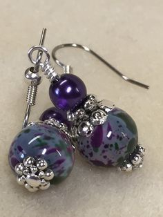 Life is short - wear pretty things! A beautiful pair of purple & olive speckled dangle earrings that will be a great wardrobe accessory. Also a great gift idea. Earrings are made using surgical steel ear wires. I use wrapped loops to give the earring a more finished look. Earrings come with rubber ear backs that slide on to keep earrings from falling out of ears. Color: dark purple, olive green, Deep purple pearl, Earrings length: 1 3/4 inches YOU MAY ALSO LIKE: https://www.etsy.com/shop/Jil Adjustable Drop Earrings With Hypoallergenic Hooks, Adjustable Hypoallergenic Drop Earrings, Adjustable Purple Jewelry With Lever Back Ear Wires, Purple Round Beaded Jewelry For Mother's Day, Hypoallergenic Czech Glass Jewelry, Hypoallergenic Purple Round Bead Earrings, Gift Hypoallergenic Drop Earrings, Purple Czech Glass Earrings For Gift, Everyday Purple Jewelry With Ear Wire