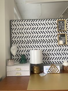 a desk with two boxes and a lamp on it next to a wallpapered headboard