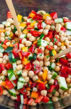 a salad with chickpeas, carrots and cucumbers in a glass bowl