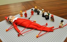 a large red object laying on top of a wooden floor next to legos and people