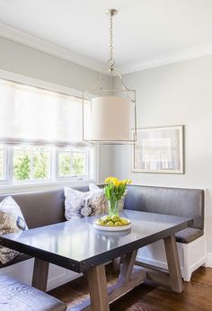 a dining room table with flowers on it in front of a couch and window sill