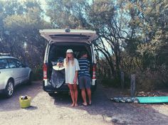 two people standing in the back of a van