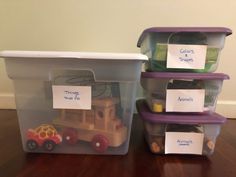 three plastic containers filled with toys on top of a wooden floor