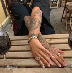 a woman sitting at a wooden table with two wine glasses on it and her hand resting on the table