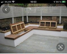 an outdoor seating area with wooden benches on the side and brick flooring around it