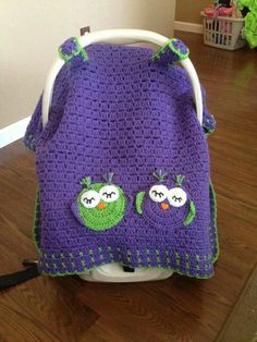 a crocheted purple and green blanket sitting on top of a wooden floor next to a white chair