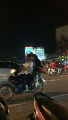 two people are riding motorcycles down the street at night in front of cars and trucks