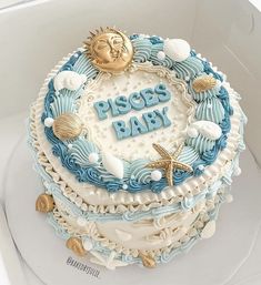 there is a blue and white cake that says piscious baby on it with shells, starfish, seashells, and sea stars